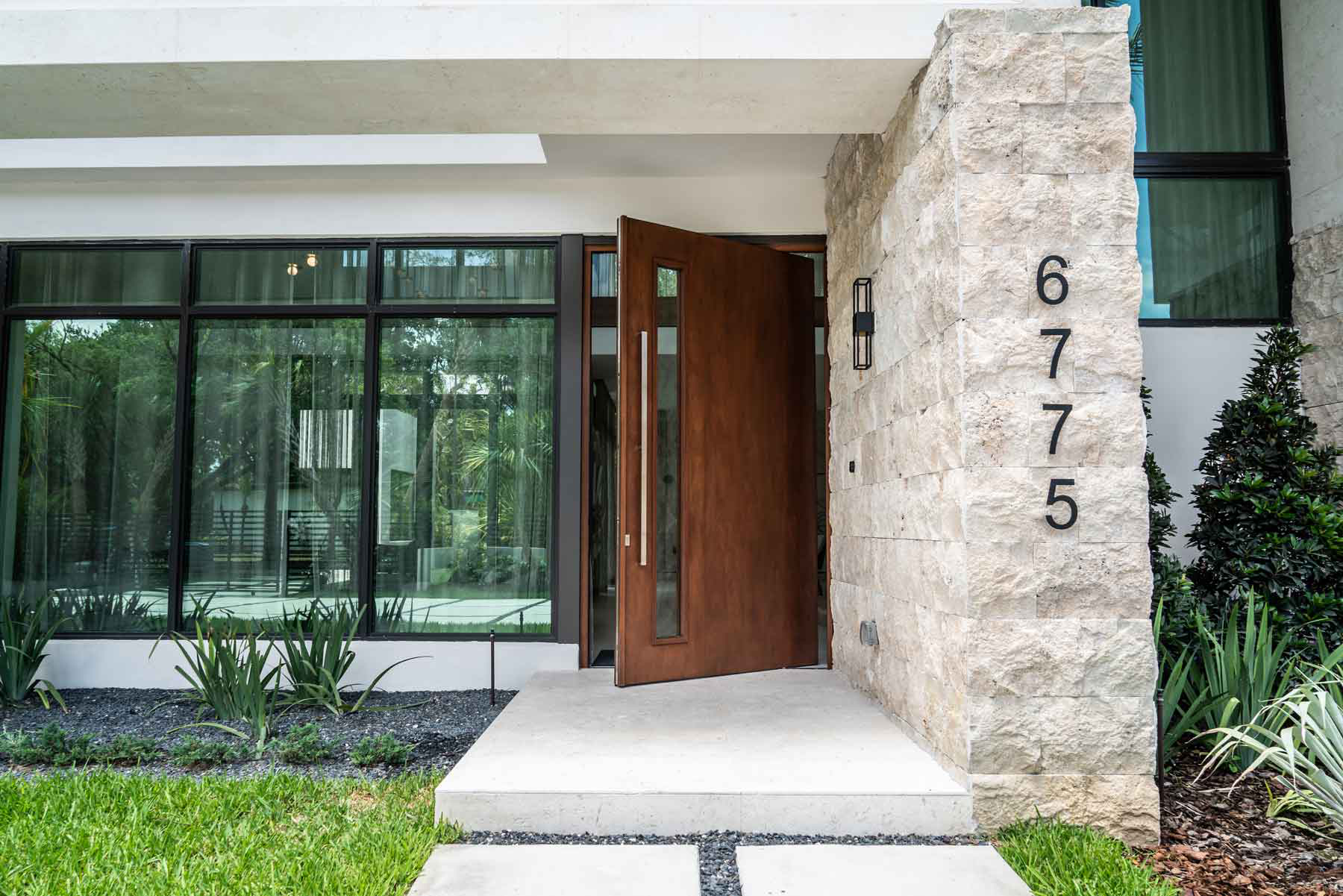 Pivot door with a glass panel, allowing natural light to illuminate the hallway of a minimalist space.