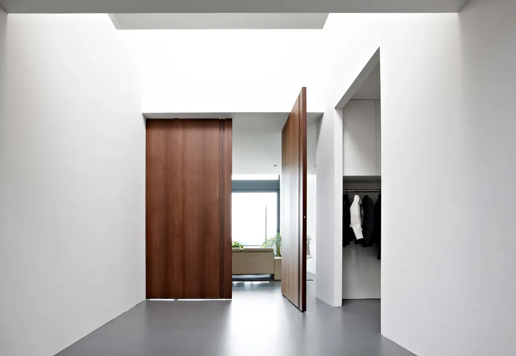 Glass pivot door connecting the living room to the patio, creating a seamless indoor-outdoor flow.